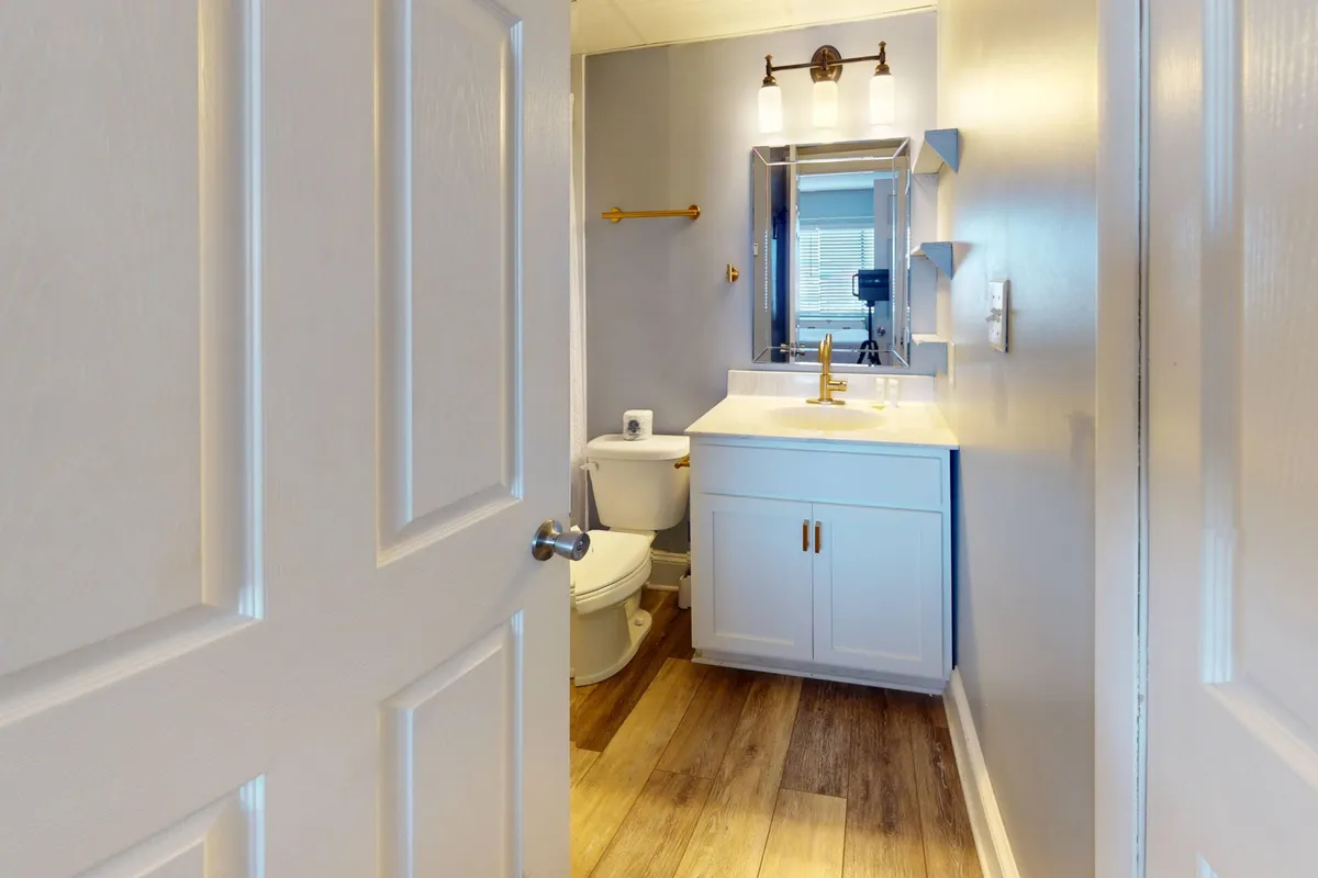 A sparkling clean bathroom with a modern vanity, large mirror, and bright light fixtures. The space is tidy and inviting, perfect for self-care routines and freshening up after the beach.