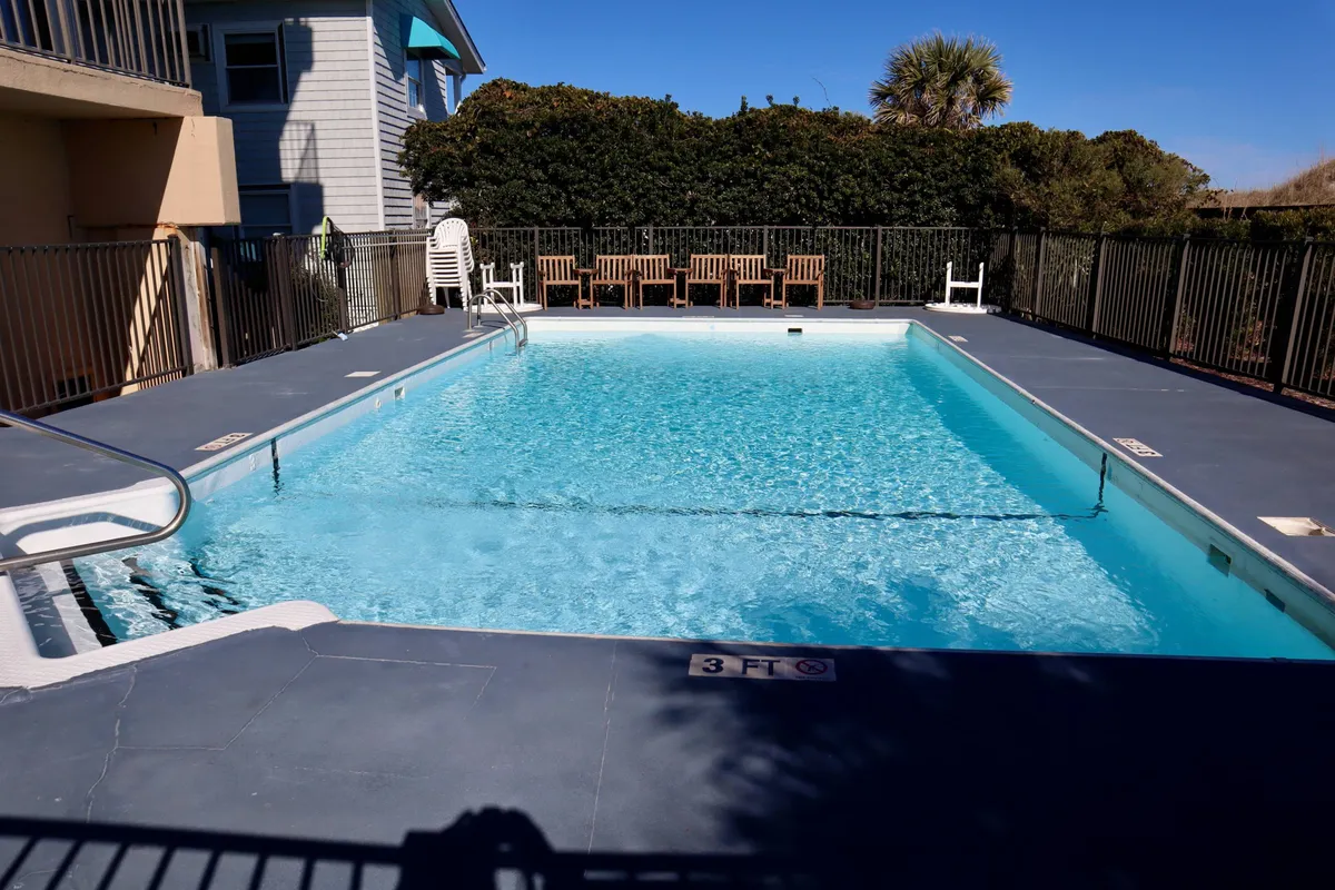 A sparkling resort-style swimming pool surrounded by lounge chairs and landscaped greenery, inviting families to relax, play, and enjoy sunny afternoons together.